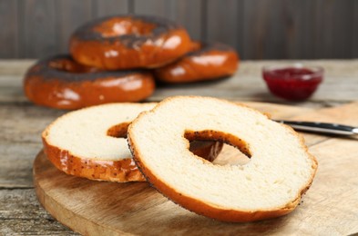 Photo of Delicious fresh halved bagel on wooden table, closeup