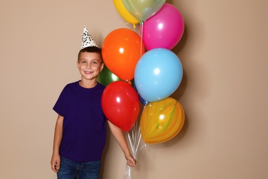 Happy boy with balloons on brown background. Birthday celebration