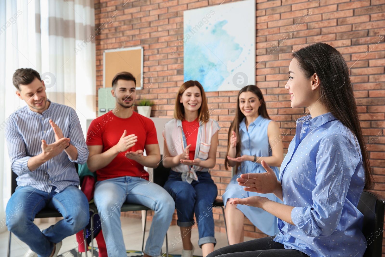 Photo of Group of young people learning sign language with teacher indoors