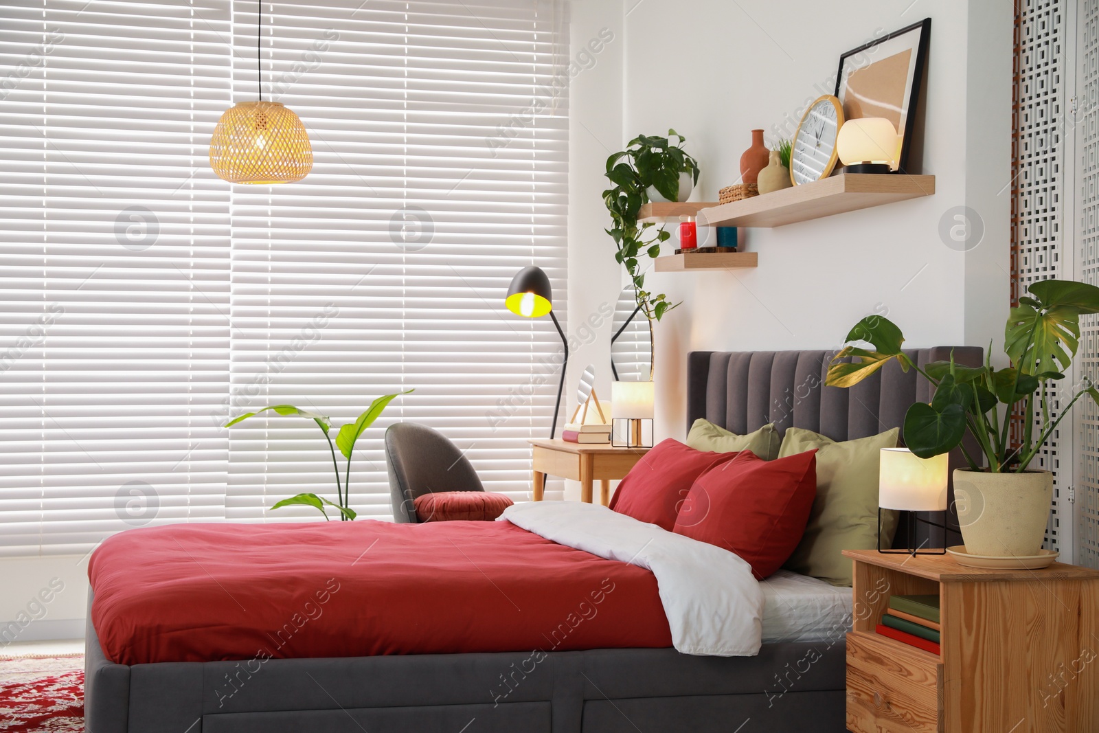 Photo of Stylish bedroom interior with comfortable bed, dressing table, lamps and green houseplants