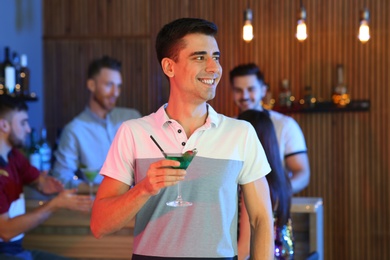 Young man with glass of martini cocktail at party