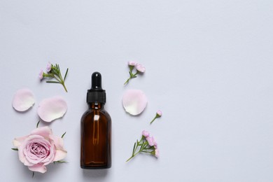 Photo of Bottle of cosmetic serum and beautiful flowers on light grey background, flat lay. Space for text