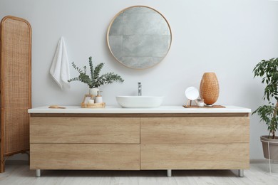 Photo of Modern bathroom interior with stylish mirror, eucalyptus branches and vessel sink