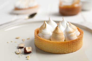 Photo of Tartlet with meringue on white plate, closeup. Delicious dessert