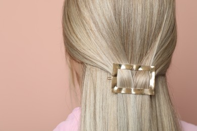 Young woman with beautiful gold hair clip on pink background, back view