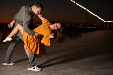 Beautiful young couple practicing dance moves in evening outdoors