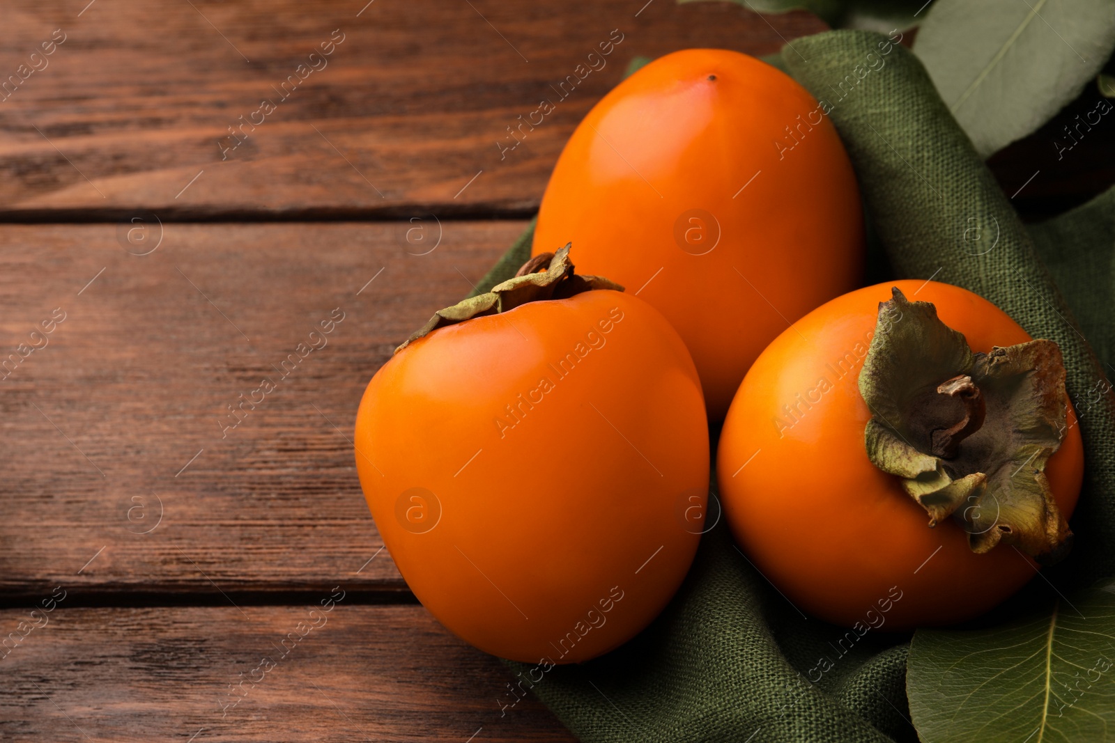 Photo of Delicious ripe juicy persimmons on wooden table