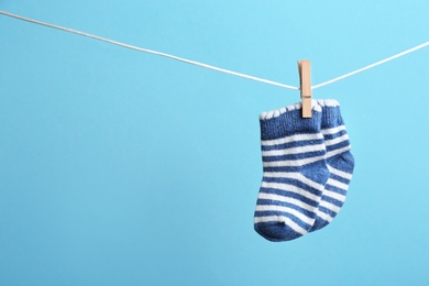 Small socks hanging on washing line against color background, space for text. Baby accessories