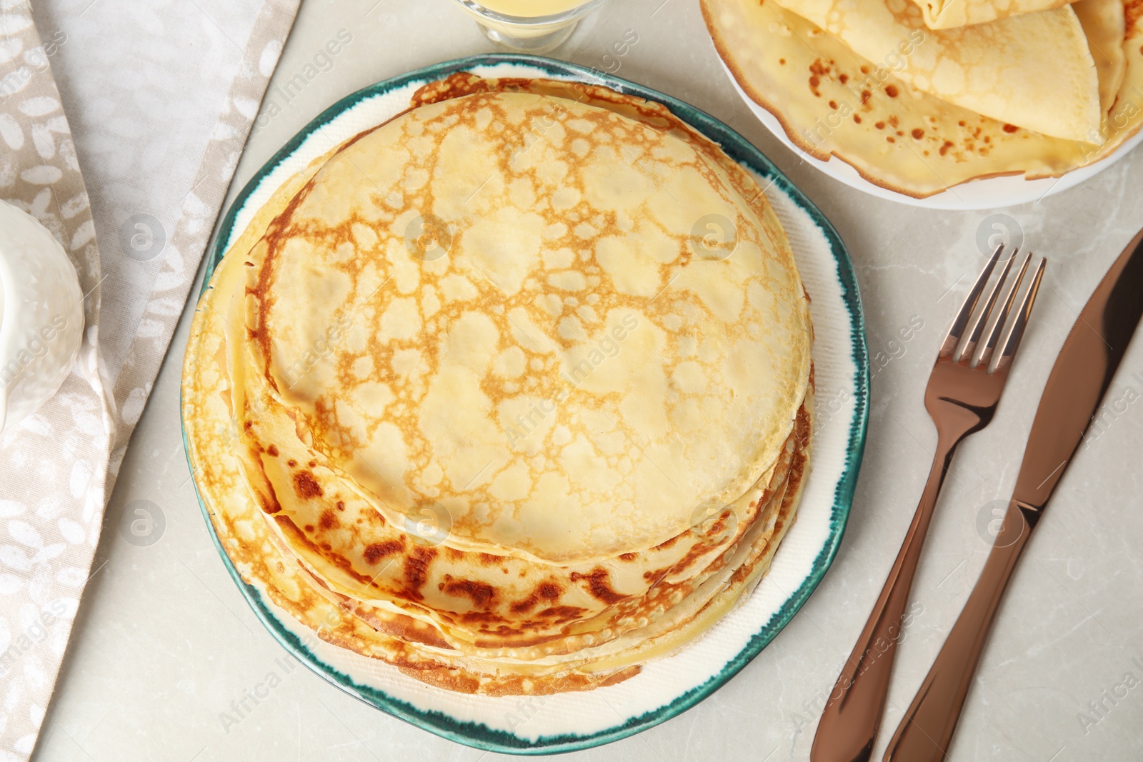 Photo of Flat lay composition with fresh thin pancakes on light grey marble table