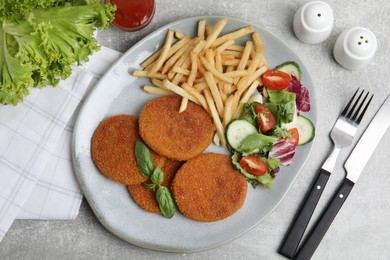 Delicious fried breaded cutlets with garnish served on grey table, flat lay