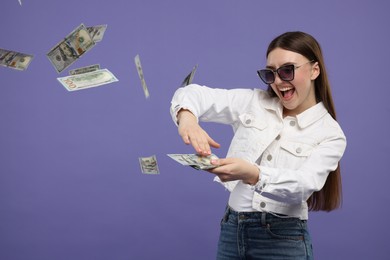 Photo of Happy woman throwing money on purple background