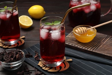 Photo of Refreshing hibiscus tea with ice cubes and mint in glass served on table