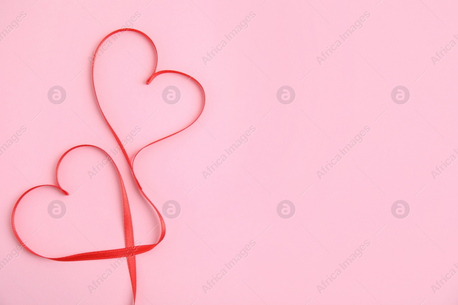 Photo of Hearts made of red ribbon on pink background, flat lay with space for text. Valentine's day celebration