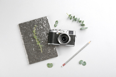 Flat lay composition with camera for professional photographer and stationery on light background