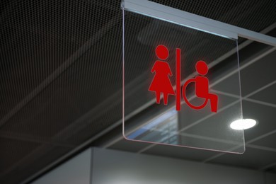 Red public toilet sign on transparent glass hanging indoors