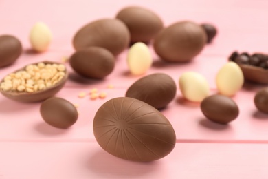 Photo of Sweet chocolate eggs on pink wooden table