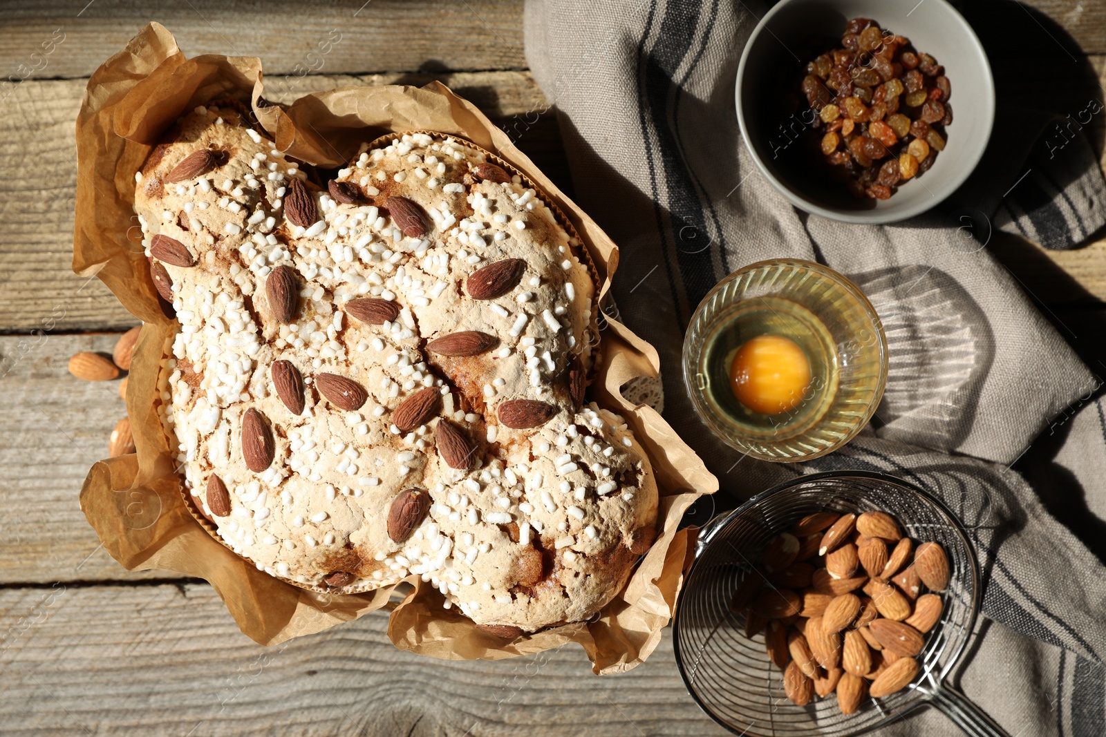 Photo of Delicious Italian Easter dove cake (traditional Colomba di Pasqua) and ingredients on wooden table, flat lay