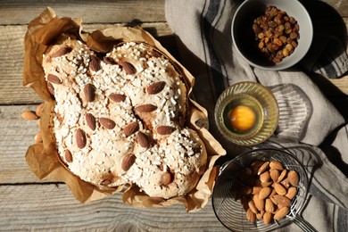 Delicious Italian Easter dove cake (traditional Colomba di Pasqua) and ingredients on wooden table, flat lay