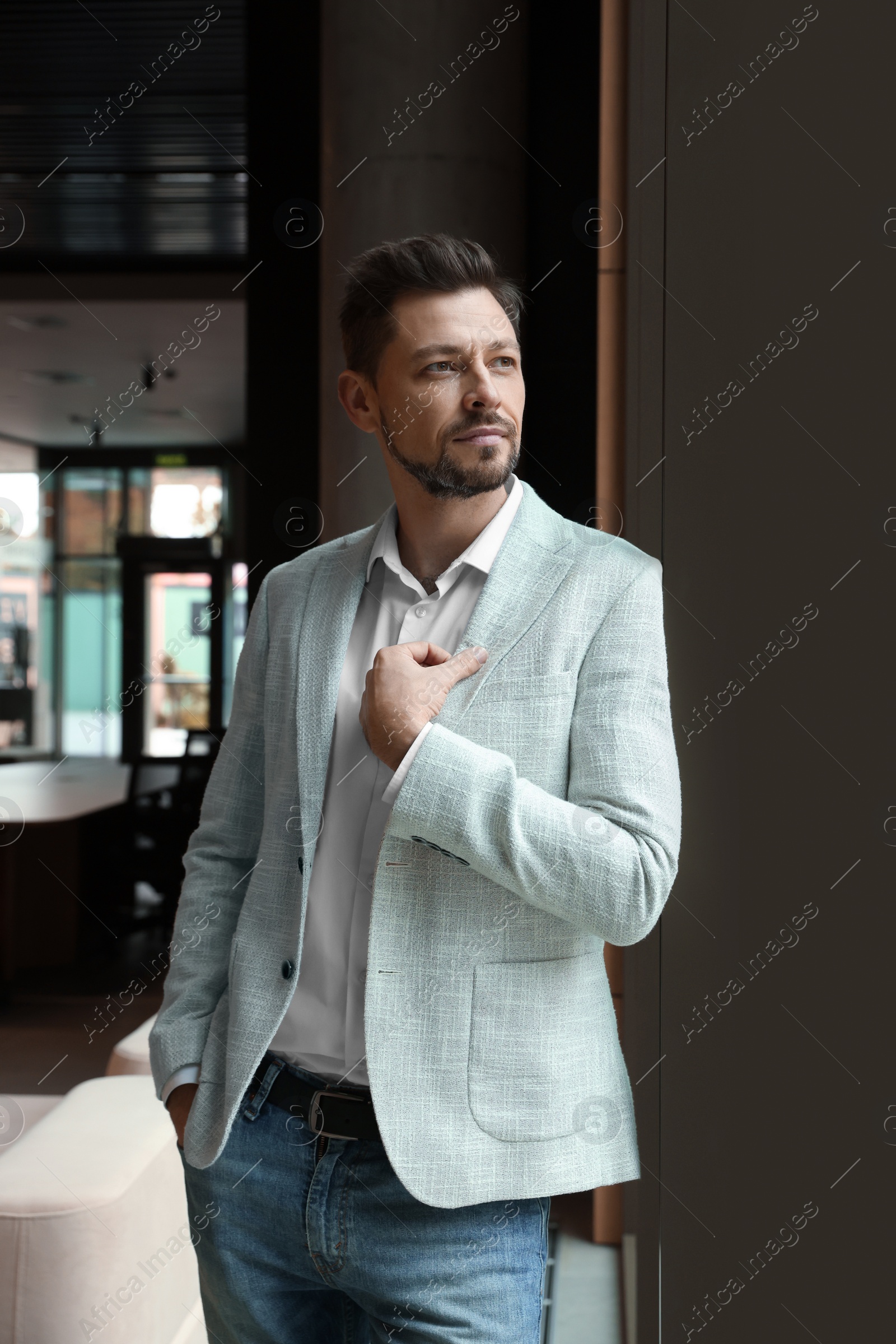 Photo of Attractive serious man wearing jacket in hall