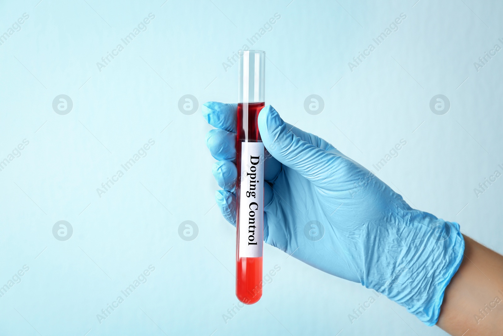 Image of Woman holding test tube with sample on light background, closeup. Doping control 