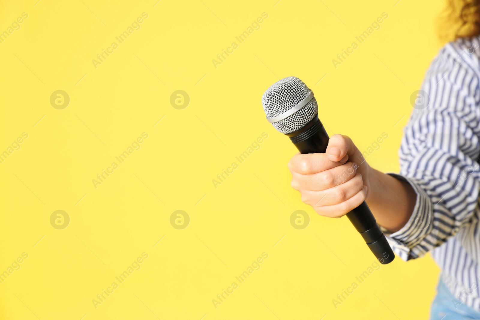 Photo of Young woman holding microphone in hand on color background. Space for text