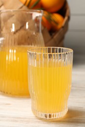 Tasty freshly made orange juice on white wooden table