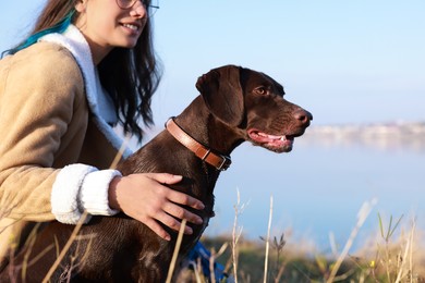 Woman with her German Shorthaired Pointer dog near river, closeup