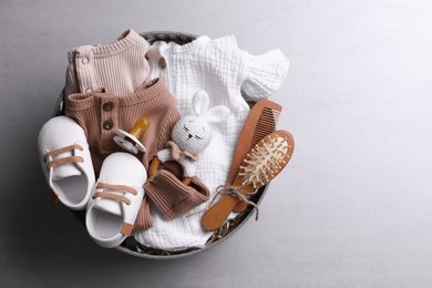 Photo of Box with baby clothes, booties and accessories on grey background, top view. Space for text
