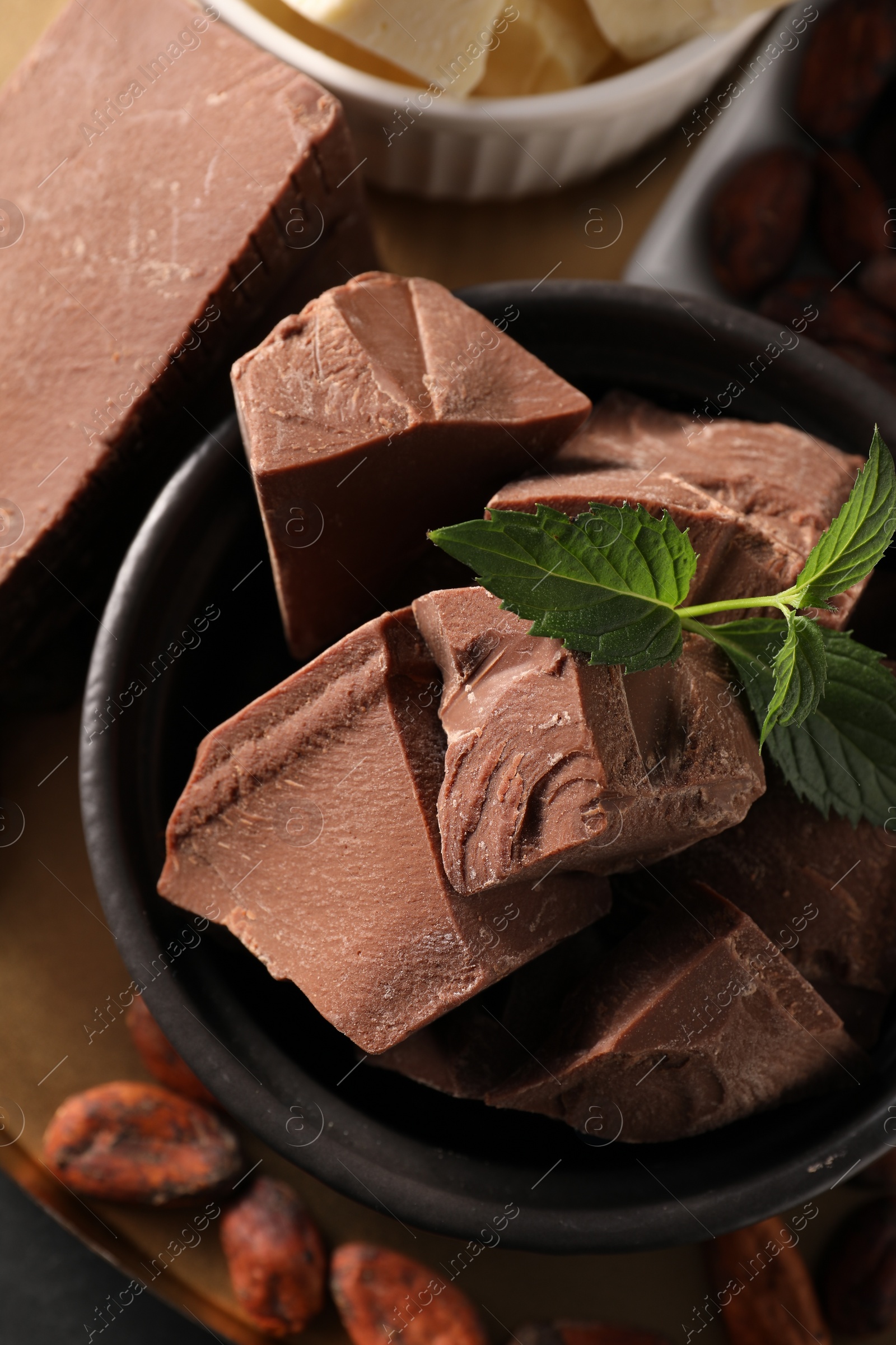 Photo of Pieces of tasty milk chocolate and mint on table, top view