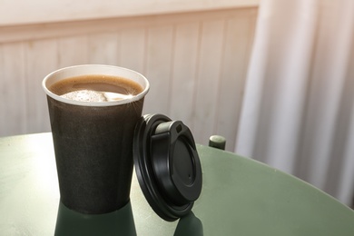 Cardboard cup of aromatic coffee with lid on table. Space for text