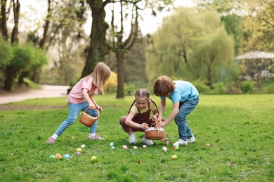 Photo of Easter celebration. Cute little children hunting eggs outdoors