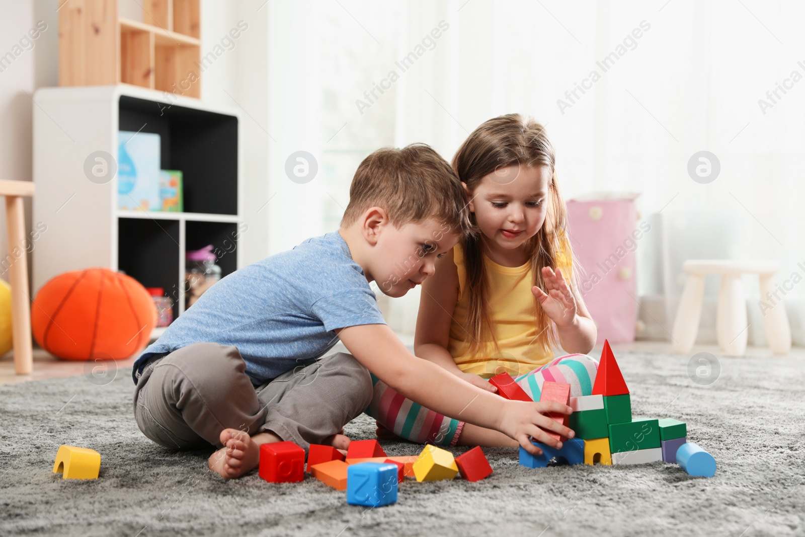 Photo of Little children playing with colorful blocks indoors