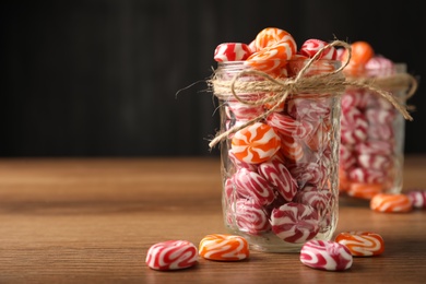 Photo of Color hard candies on wooden table. Space for text