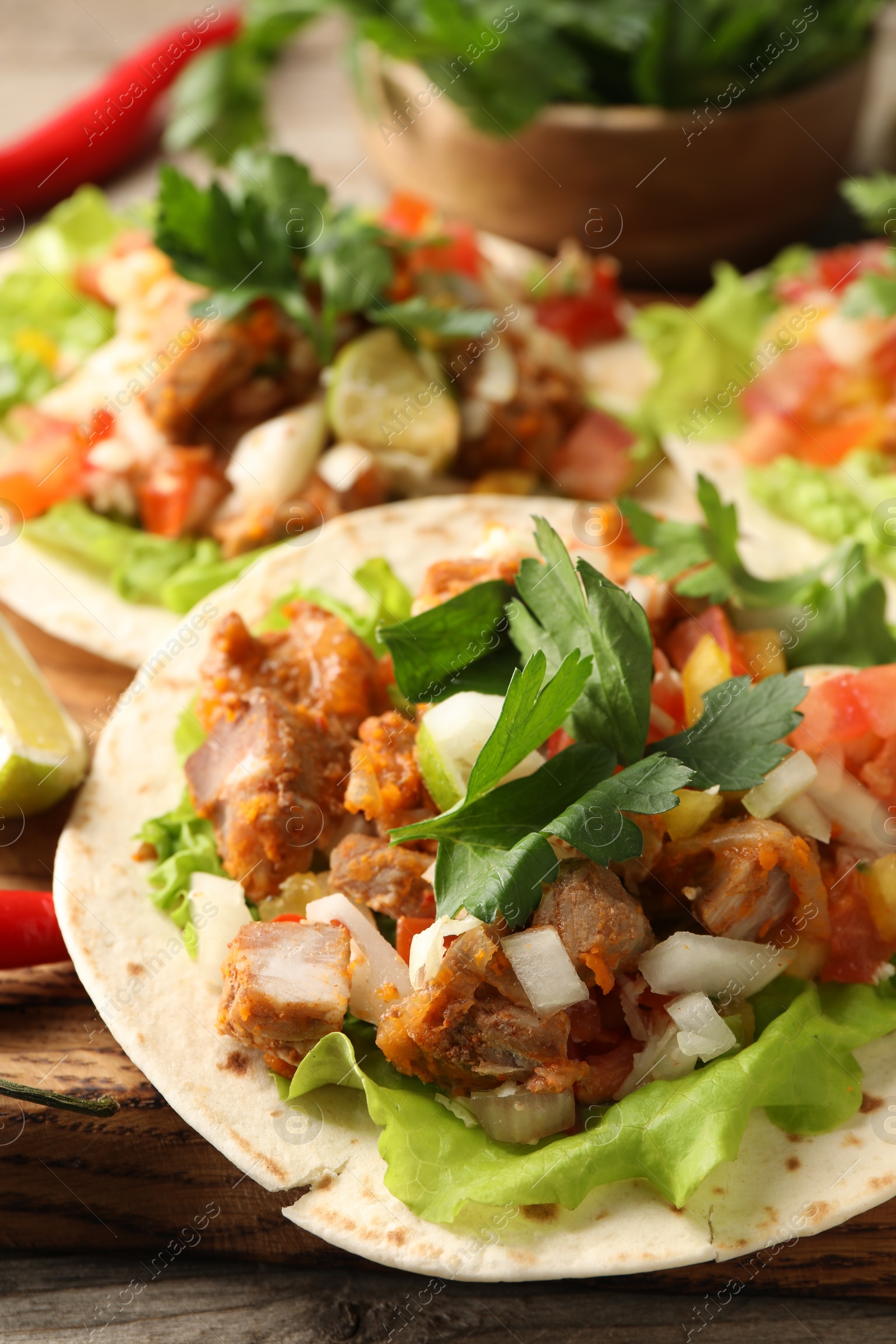 Photo of Delicious tacos with vegetables and meat on table, closeup