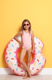 Photo of Cute little girl with bright inflatable ring near color wall