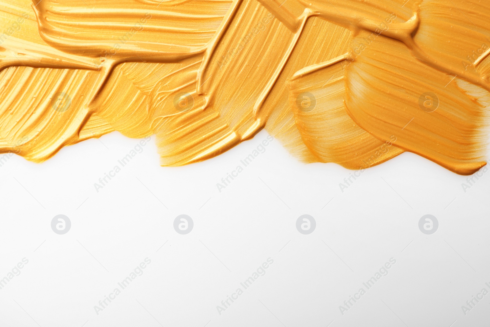 Photo of Strokes of gold paint isolated on white, top view