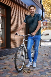 Photo of Man with bicycle on street near wooden wall