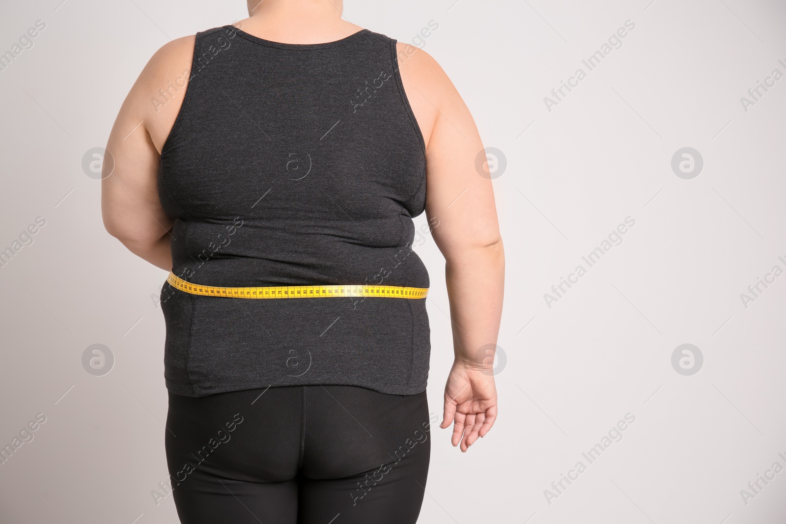 Photo of Overweight woman with measuring tape on light background