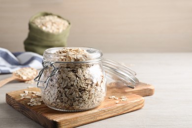 Photo of Glass jar with oatmeal on white wooden table. Space for text