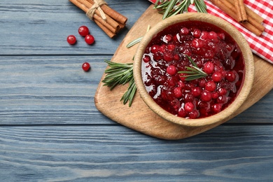 Flat lay composition with cranberry sauce, rosemary and cinnamon on blue wooden table, space for text