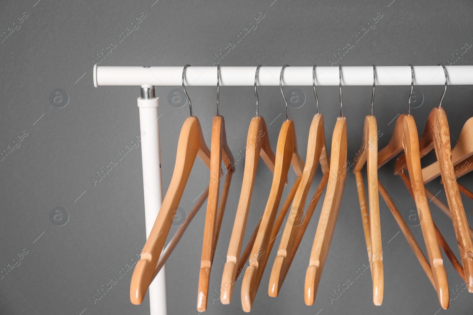 Photo of Clothes rail with wooden hangers on gray background