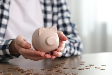 Photo of Financial savings. Man with piggy bank at wooden table