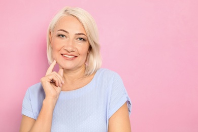 Photo of Portrait of mature woman with beautiful face on pink background. Space for text