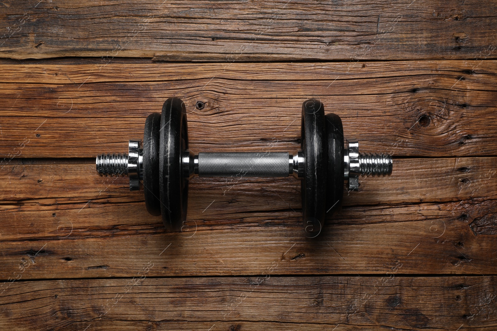 Photo of One barbell on wooden floor, top view