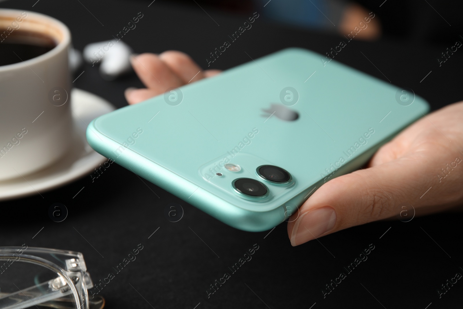 Photo of MYKOLAIV, UKRAINE - JULY 9, 2020: Woman holding Iphone 11 Green at table, closeup