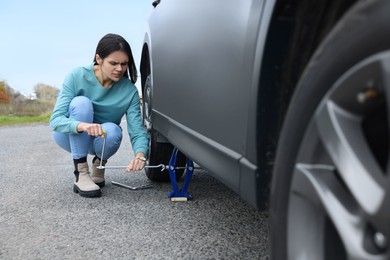 Photo of Young woman changing tire of car on roadside
