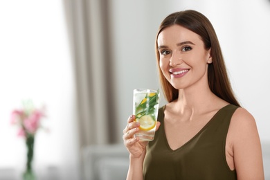 Photo of Young woman with lemonade at home. Refreshing drink