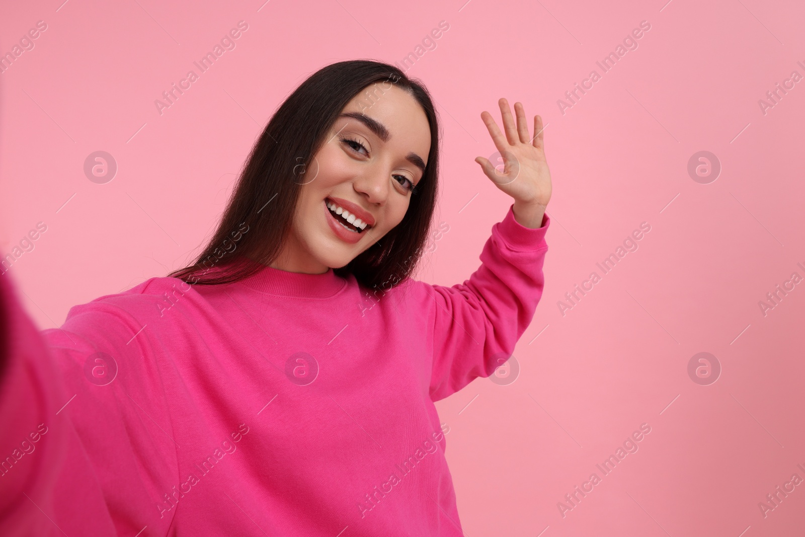 Photo of Smiling young woman taking selfie on pink background, space for text