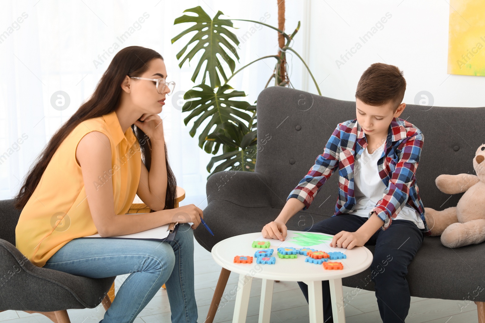 Photo of Child psychologist working with boy in office