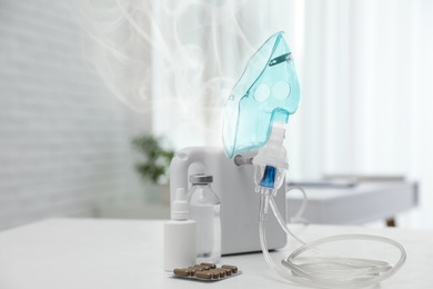 Image of Modern nebulizer with face mask on white table indoors. Inhalation equipment